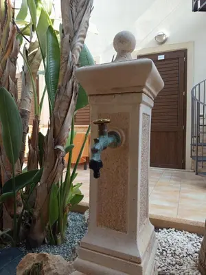 a stone water fountain in the middle of a garden at Amaryllis Hotel in San Vito lo Capo