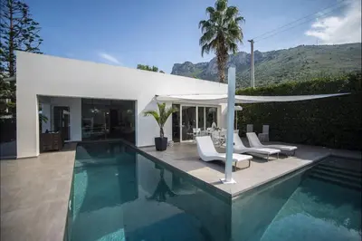 a swimming pool with chairs and an umbrella at Villa Corallo in Cinisi