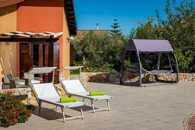 a patio with two lounge chairs and a tent at Villa Thyrrenia in Castellammare del Golfo