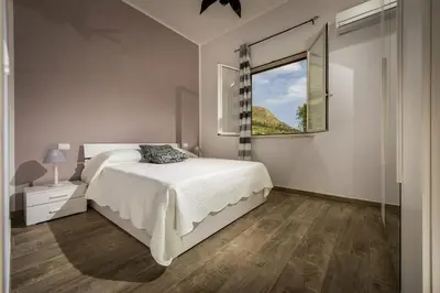a white bedroom with a bed and a window at Villa Gea in Castellammare del Golfo