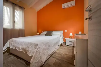 a bedroom with a white bed and an orange wall at Villa Gea in Castellammare del Golfo
