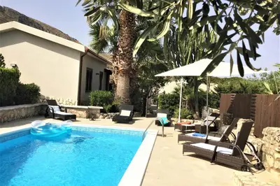 a swimming pool with chairs and an umbrella next to a house at Villa Isabella in Castellammare del Golfo