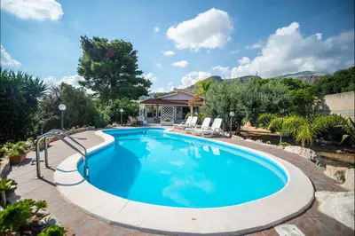 a swimming pool in a yard with chairs and a house at Villa La Randa in Castellammare del Golfo