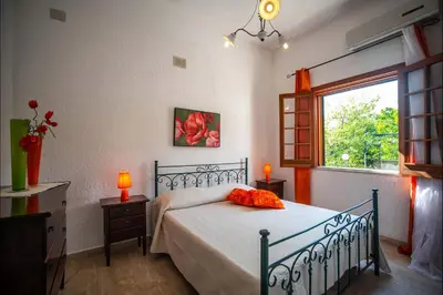 a bedroom with a bed with red flowers on it at Villa La Randa in Castellammare del Golfo