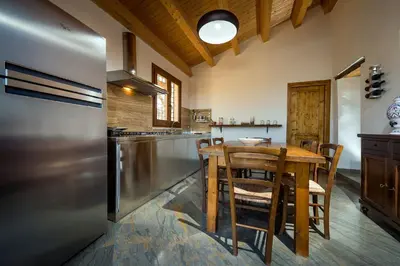 a kitchen with a wooden table and a refrigerator at Villa Thalia in Castellammare del Golfo