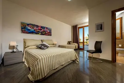 a bedroom with a bed and a chair at Villa Thalia in Castellammare del Golfo