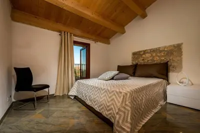 a bedroom with a bed and a chair and a window at Villa Thalia in Castellammare del Golfo