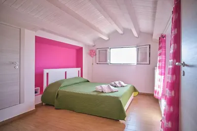 a bedroom with a green bed and pink walls at Villa Sicilia in Lascari