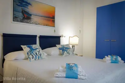 a bedroom with a blue and white bed with towels on it at VILLA ROSETTA ampi spazi esterni WIFI FREE in Trabia