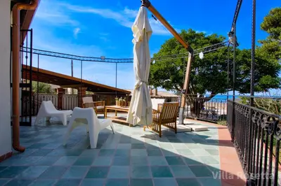 a patio with white chairs and an umbrella at VILLA ROSETTA ampi spazi esterni WIFI FREE in Trabia