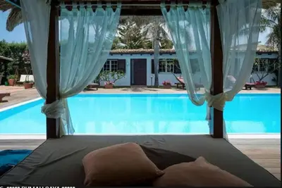 a bed with a canopy in front of a pool at RUMAH SAYA in Campofelice di Roccella