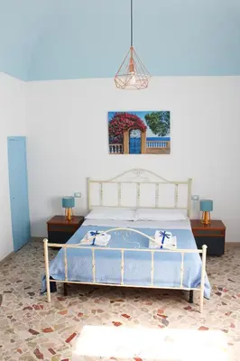 a bedroom with a bed and two tables and a painting at Narciso Blu in Castellammare del Golfo