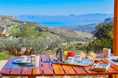 a wooden table with coffee cups and pastries on it at Villa Montemar in Balata di Baida