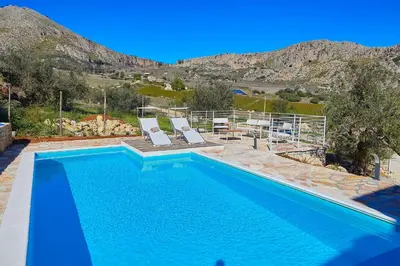 a swimming pool with two lounge chairs next to a mountain at Villa Montemar in Balata di Baida