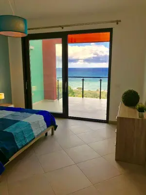 a bedroom with a view of the ocean through a sliding glass door at Red Luxury in Borgo Guardiola near Cefalù in Mandra Capreria