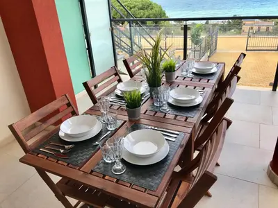 a wooden table with plates and glasses on a balcony at Red Luxury in Borgo Guardiola near Cefalù in Mandra Capreria