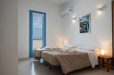 a bedroom with two beds and a large window at Casa Azzurra sul mare e centralissima in San Vito lo Capo