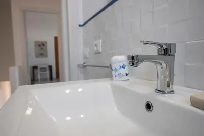 a bathroom sink with a faucet and a cup on it at Casa Blu sul mare e centralissima in San Vito lo Capo