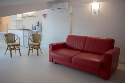 a red couch in a living room with a kitchen at Duchessa House in Castellammare del Golfo