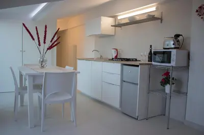 a white kitchen with a table and a microwave at Duchessa House in Castellammare del Golfo