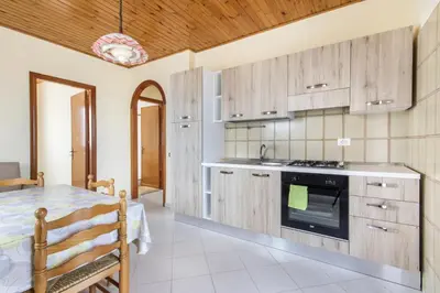 a kitchen with wooden cabinets and a table in a room at Residence le Coccinelle vicino a Cefalù in Campofelice di Roccella