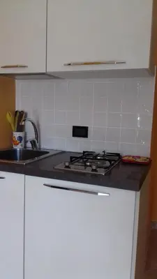 a kitchen with a stove and a sink and white cabinets at Suites Mondello Deluxe in Mondello