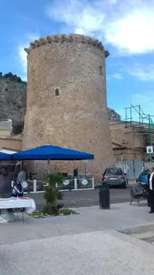 a large brick building with a blue umbrella in front of it at Suites Mondello Deluxe in Mondello
