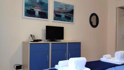 a bedroom with a blue dresser with a tv on it at Suites Mondello Deluxe in Mondello
