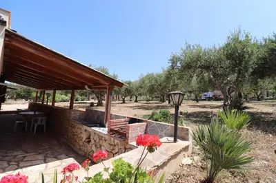 a building with a table and flowers in a yard at EVEN HAVEN Baglio in San Vito lo Capo