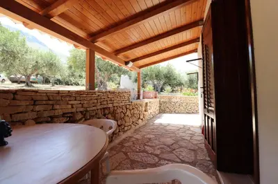 a patio with a stone wall and a table and chairs at EVEN HAVEN Baglio in San Vito lo Capo
