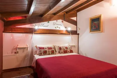 a bedroom with a red bed in a room with wooden ceilings at The Normans Apartments in Palermo