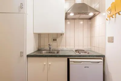 a kitchen with white cabinets and a sink at The Normans Apartments in Palermo