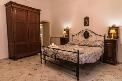 a bedroom with a bed and a wooden cabinet at Appartamento Palazzo Pace al Cassaro in Palermo