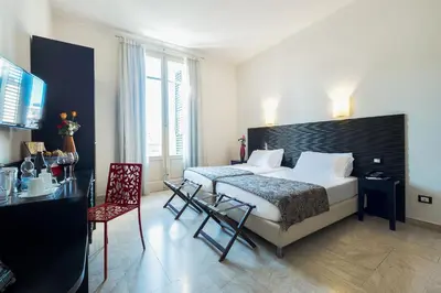 a hotel room with a bed and a table and chairs at Hotel Garibaldi in Palermo