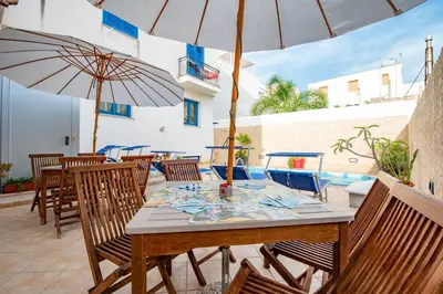 a wooden table with chairs and umbrellas on a patio at Hotel Altamarea in San Vito lo Capo