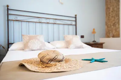 a straw hat and two starfish on a bed at Hotel Altamarea in San Vito lo Capo