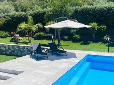 a patio with two chairs and an umbrella next to a pool at flAle's holiday house in Cefalù