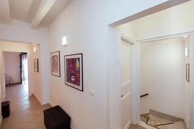 a white hallway with paintings on the walls at Camere Simona in Castellammare del Golfo