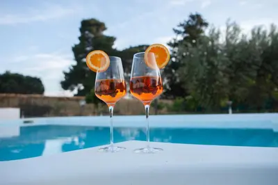 two wine glasses with oranges in them next to a swimming pool at RESORT Valle del Re in Partinico