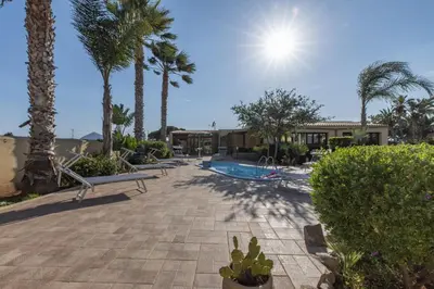 a resort with a swimming pool and palm trees at Villa Minoa con piscina in San Vito lo Capo