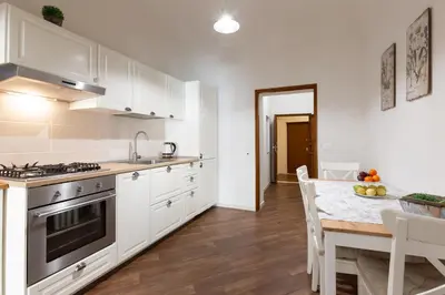 a kitchen with white cabinets and a table with a dining room at GuestHost - Quattro Canti Charming Flat in Palermo