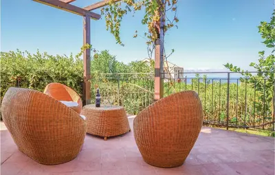 a patio with three wicker chairs and a table at Villa Joly in Terrasini