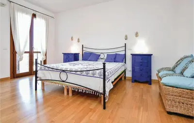 a bedroom with a bed and a blue chair at Villa Joly in Terrasini