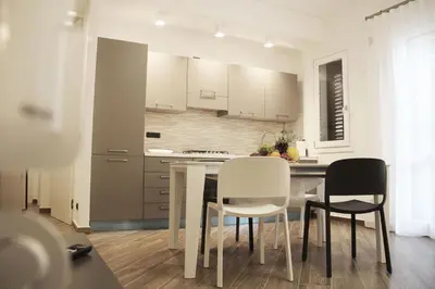 a kitchen with white cabinets and a table and chairs at Mamiani Suite in Castellammare del Golfo