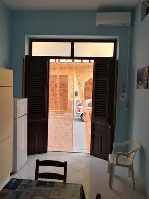 a kitchen with an open door with a chair and a table at Short Lets Vacanze 