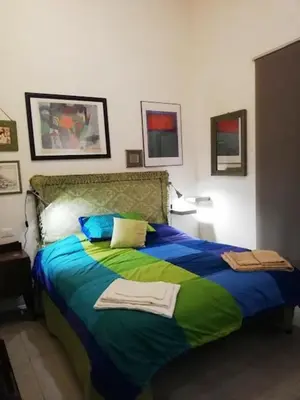a bedroom with a large bed with blue and green sheets at Arimatea Accommodations in Palermo