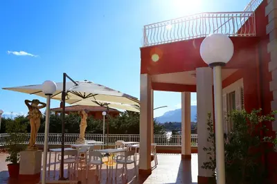 a patio with tables and umbrellas next to a building at Villa Edera Rental Room in Santa Flavia