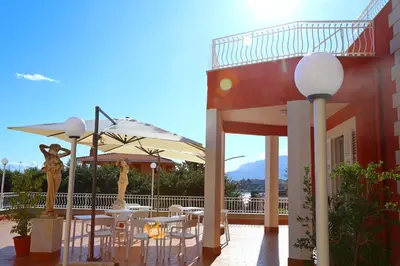 a patio with tables and umbrellas on a building at Villa Edera Rental Room in Santa Flavia