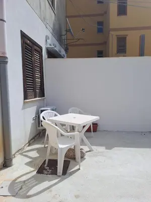 a white table and two chairs next to a building at Appartamenti Duchessa in Castellammare del Golfo