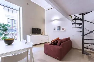 a living room with a red couch and a spiral staircase at SpAsimoH-1 in Palermo